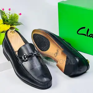 Black Clarks Loafers With A Metal Buckle And Patterned Leather
